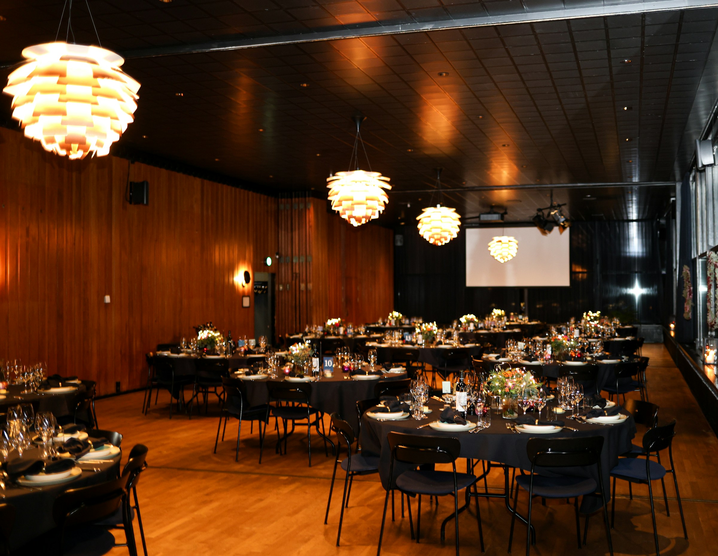 Round tables and presentation screen set up for a gala